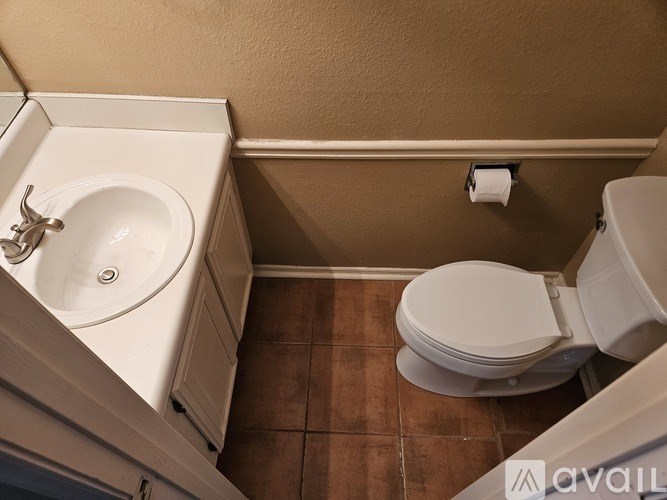 A bathroom with a toilet, sink, and toilet paper roll.