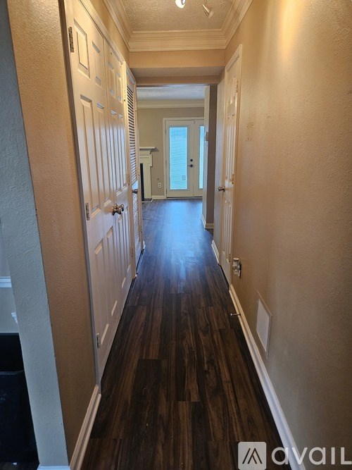 A long hallway with wood floors and white walls.