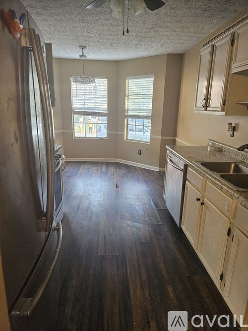 A kitchen with wooden floors and a stainless steel refrigerator.