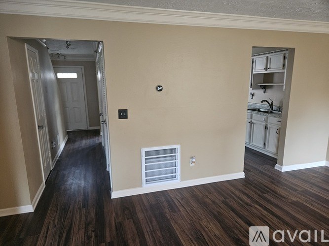 A room with a wood floor and a wall-mounted heater.