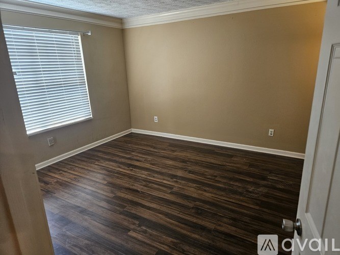 A room with wooden flooring and a window with blinds.