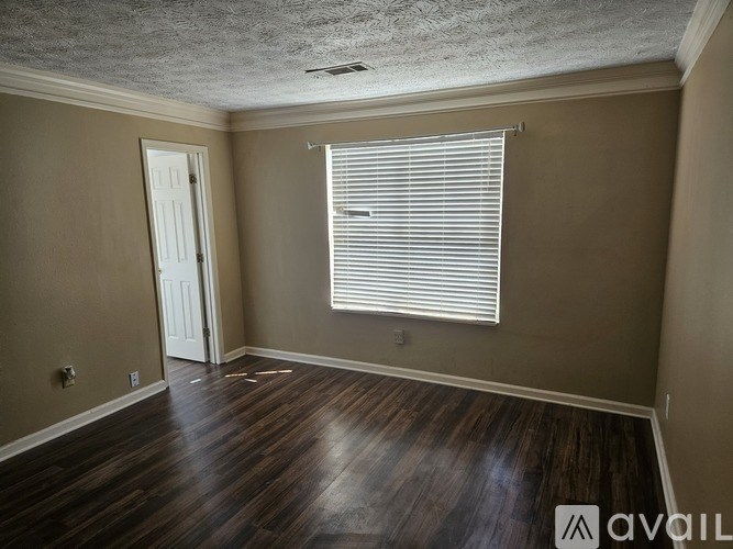 A room with wooden floors and a window with blinds.
