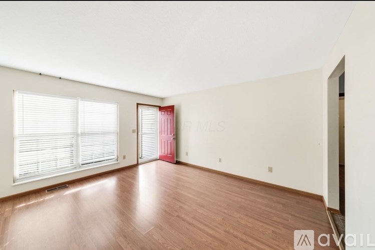 A room with wooden flooring and a pink door.