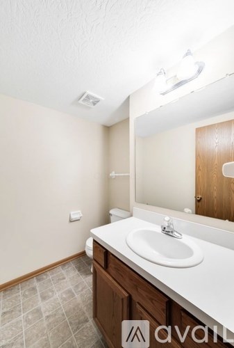 A bathroom with a sink, mirror, and wooden cabinetry.