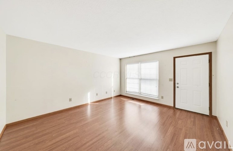 A room with wooden floors and white walls, with a door and a window.
