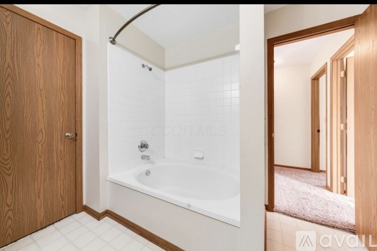 A bathroom with a white tub and a wooden door.