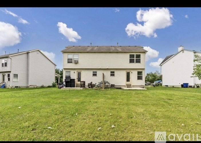 A white house with a brown roof is surrounded by a grassy yard.