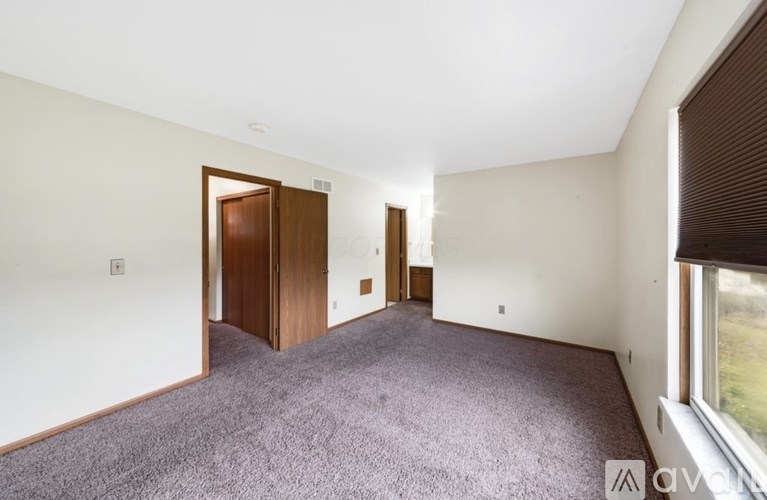 A room with a carpeted floor and two doors.