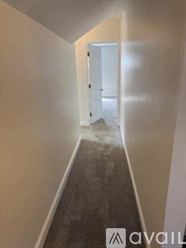 A hallway with a carpeted floor and white walls.