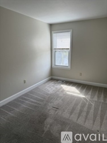 A room with a carpeted floor and a window.