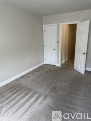 A room with a carpeted floor and two white doors.