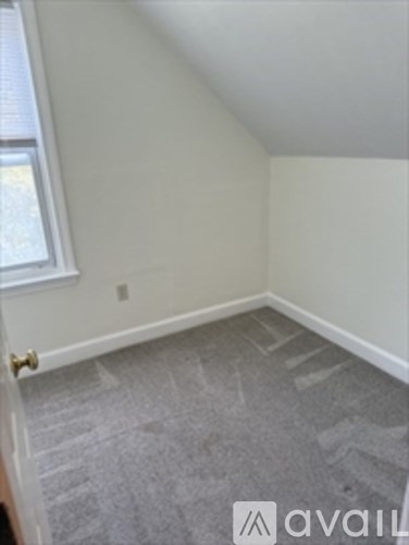 A room with a carpeted floor and a window.