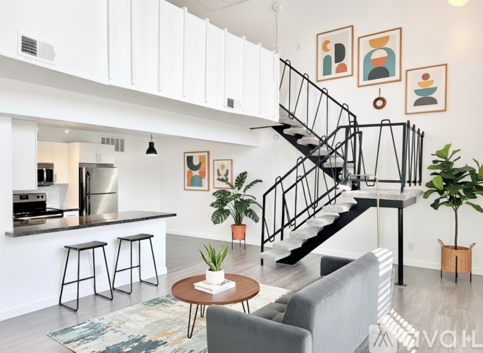 A living room with a grey couch, a coffee table, and a staircase.