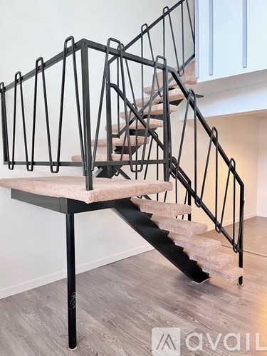A staircase with a metal railing and a beige carpeted runner.
