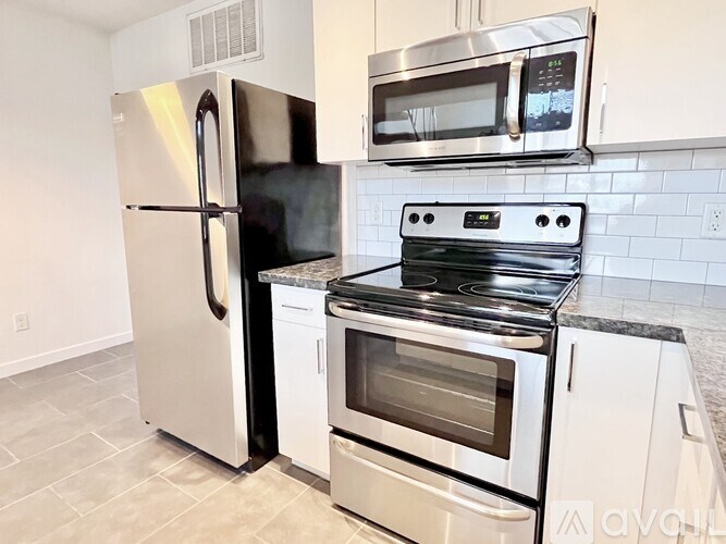 A kitchen with a stainless steel refrigerator, microwave, and oven.