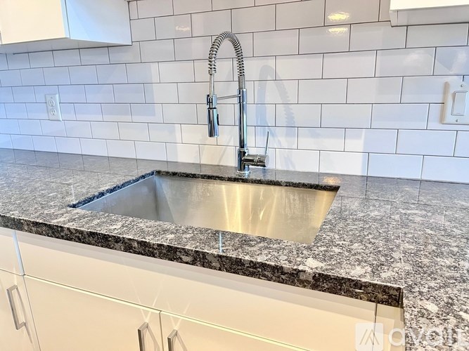 A kitchen sink with a granite countertop and a chrome faucet.