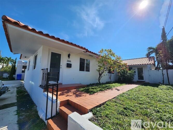A white house with a red tile roof and a black gate.