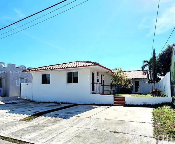 A white house with a red tile roof and a small porch.