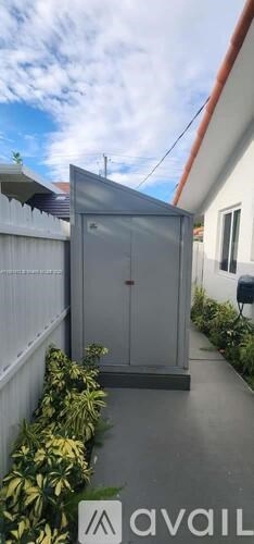 A grey metal shed is situated in a garden.