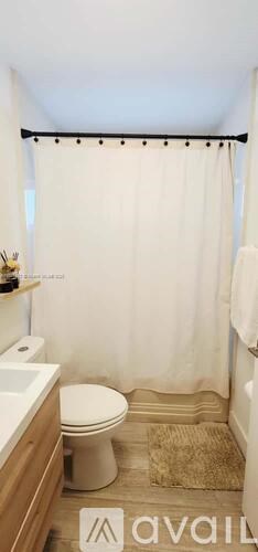 A bathroom with a toilet, sink, and shower curtain.