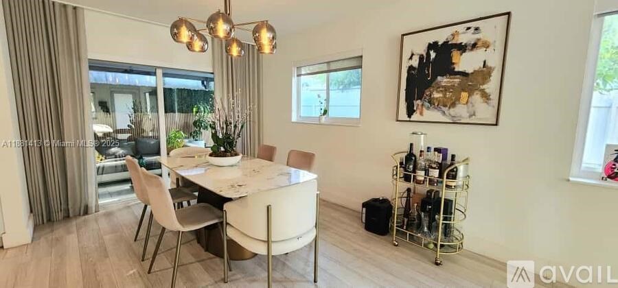 A dining room with a table set for four and a chandelier hanging from the ceiling.