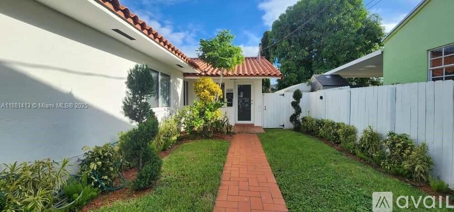 A white house with a red tile roof and a white picket fence.