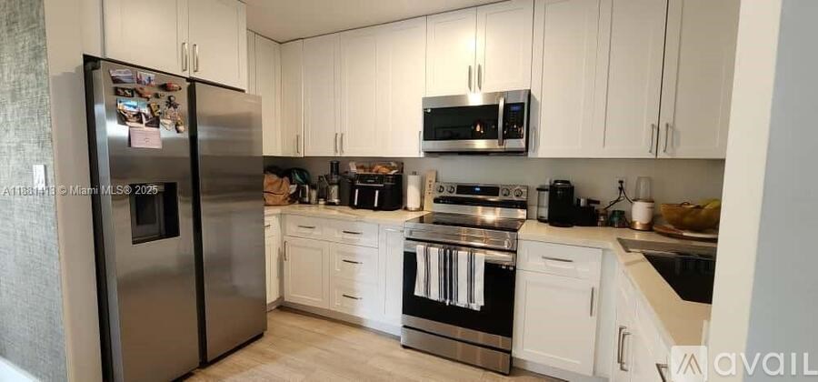 A kitchen with a refrigerator, microwave, oven, and sink.