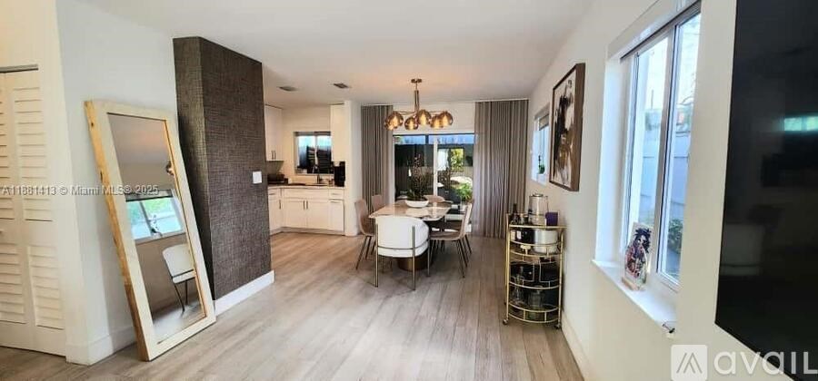 A well-lit, spacious kitchen and dining area with a large mirror and a wooden floor.