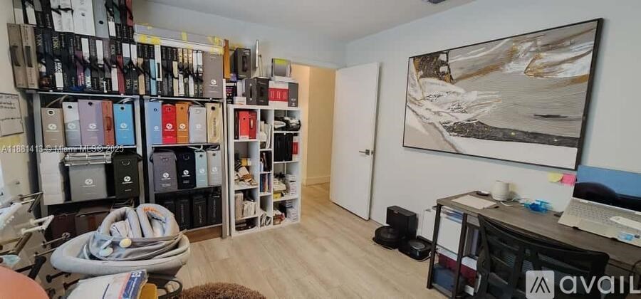 A room with a large bookshelf filled with books and a painting hanging on the wall.