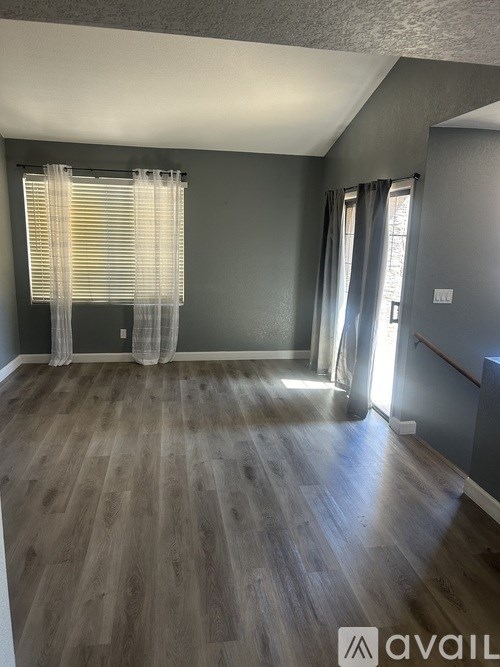 A room with wooden flooring and a window with curtains.