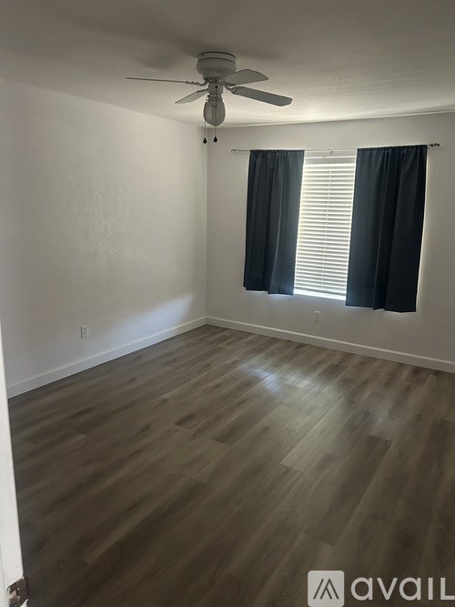 A room with a ceiling fan and wooden flooring.