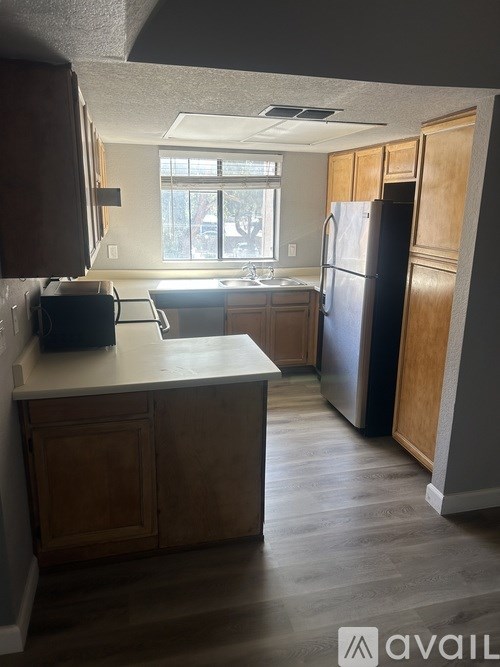 A kitchen with wooden cabinets and a black refrigerator.
