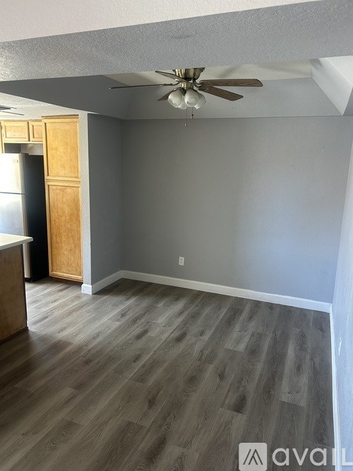 A room with a ceiling fan and wooden flooring.