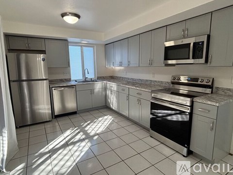 A kitchen with white cabinets and appliances is available for rent.