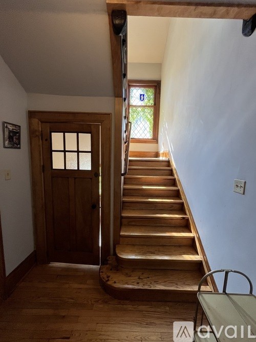 A wooden staircase with a metal handrail leads up to a door.