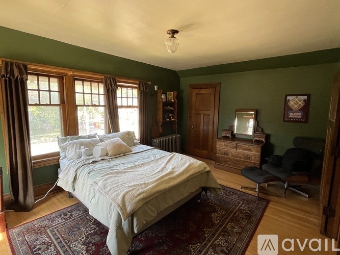 A bedroom with a bed, chair, and a rug.