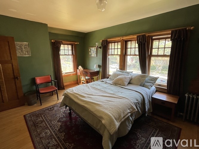 A bedroom with a large bed and a window with curtains.
