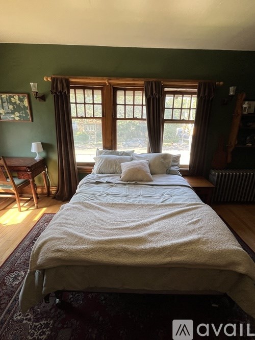 A bedroom with a large bed and a window with curtains.