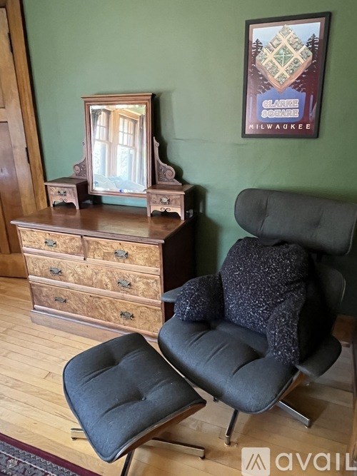 A chair and a dresser with a mirror in a room.