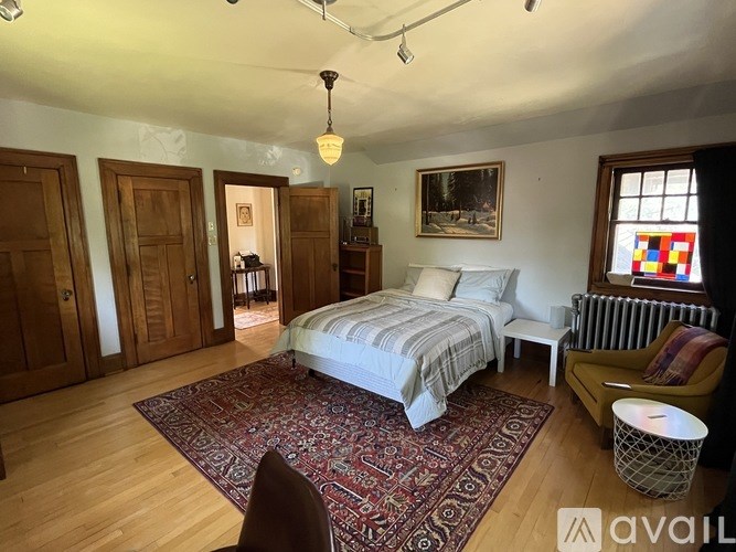 A bedroom with a bed, chair, and a rug.