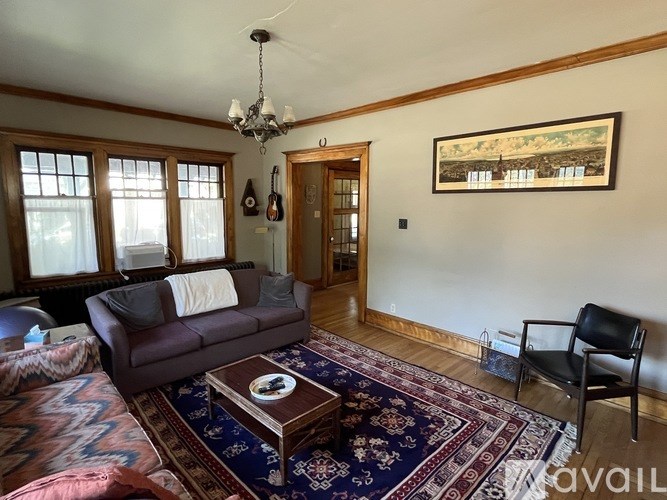 A living room with a brown couch and a rug.