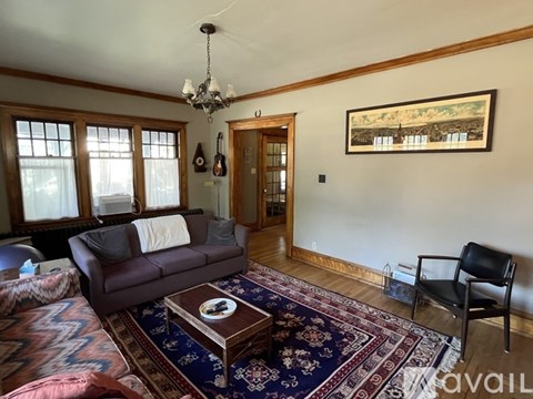 A living room with a brown couch and a rug.