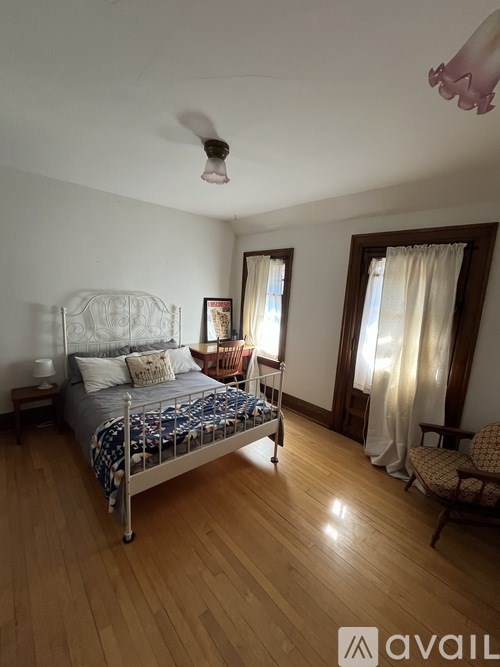 A bedroom with a bed, chair, and window.