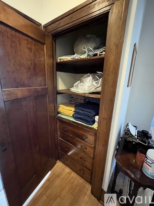 A wooden wardrobe with shoes and clothes on the shelves.