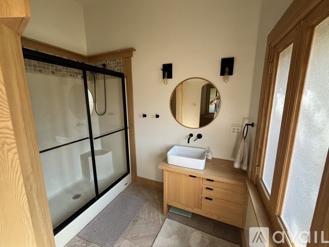 A bathroom with a sink, mirror, and shower.