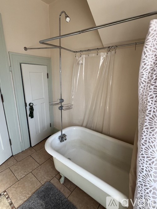 A white bathtub with a shower head and curtain.