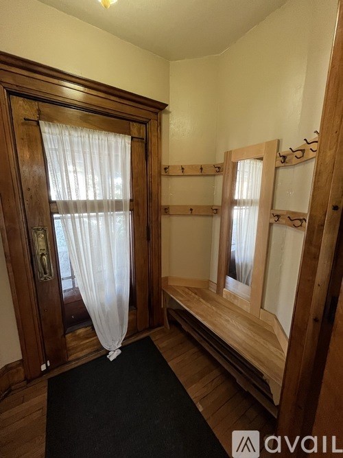 A room with a black carpet and a wooden door with a curtain.