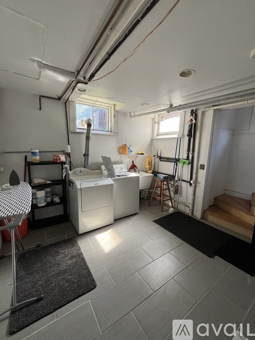 A laundry room with a washer and dryer, a chair, and a rug.