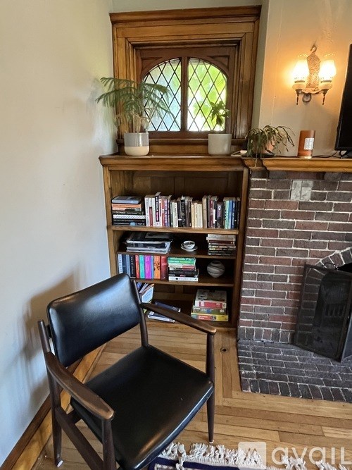 A black chair sits in front of a bookshelf with a fireplace in the background.