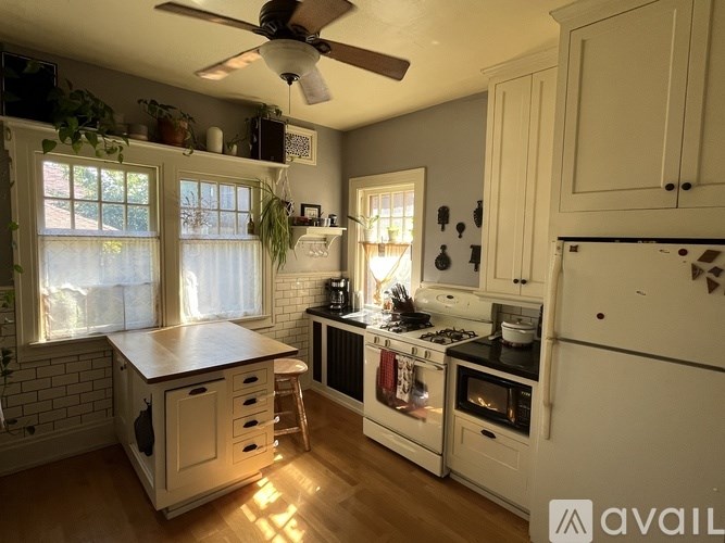 A kitchen with a white refrigerator, a wooden countertop, and a ceiling fan.